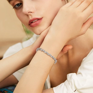 Close-up of elegant flower shaped silver links with sparkling zircons on female wrist