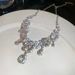 Macro shot of sparkling crystal flower teardrop pendant necklace on white ceramic