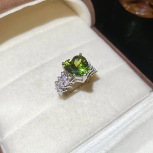 Close-up of heart-shaped green zircon ring set in polished silver on velvet box