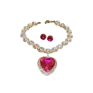 Luxury geometric gold necklace and earring set featuring a large pink heart-shaped crystal