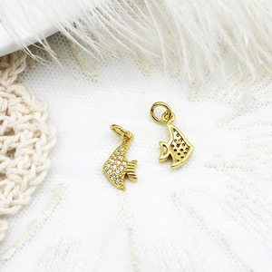 Macro shot of gold tropical fish charm with micro-paved white zircons on lace background