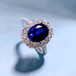 Close-up of luxury oval blue sapphire ring with sparkling halo and heart-shaped shadow