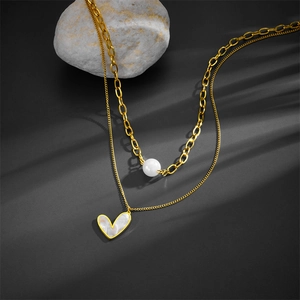 Close-up detail of double layer gold stainless steel necklace with heart and pearl