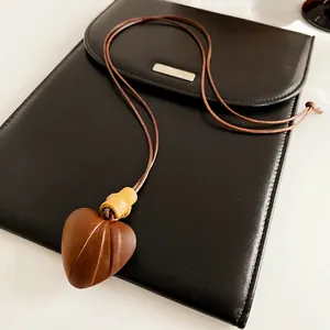 Retro wooden heart pendant necklace with bamboo accents on minimalist black background