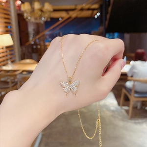 Détail d'un collier pendentif papillon doré orné de pierres de zircone brillantes