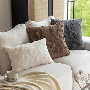 Detailed plush pillows in white, brown, and grey with 3D leaf embroidery on a sofa