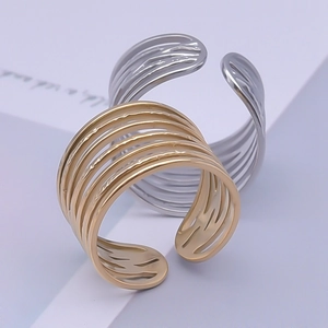 Detail of minimalist multilayer steel rings in gold and silver finish with open design