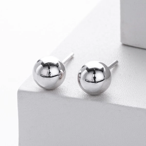 Macro shot of polished S925 sterling silver ball stud earrings on white pedestal