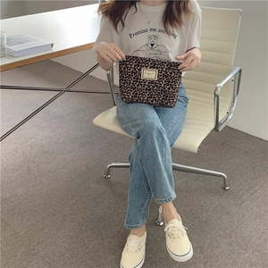 Model holding a stylish leopard print canvas makeup bag with a minimalist logo patch
