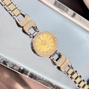 Gros plan d'une montre de luxe pour femme avec lunette en strass et cadran quartz doré
