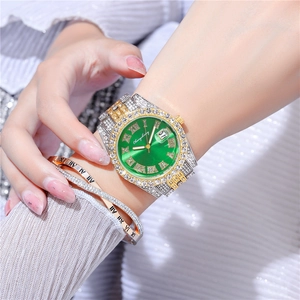 Makroaufnahme einer gold-silbernen Uhr mit grünem Zifferblatt und Strassarmband-Set