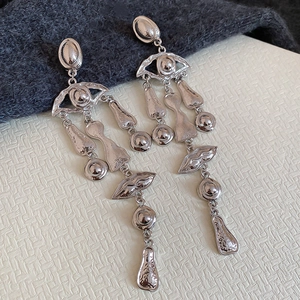 Artistic silver earrings featuring surreal eye and lip designs with fluid metal tassels