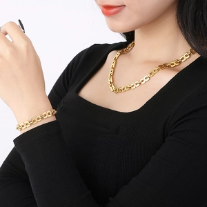 Détail d'un ensemble de collier et bracelet dorés en acier inoxydable sur un mannequin