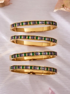 Detail of four golden bracelets set with multicolored baguette cut cubic zirconia