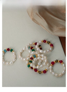 Macro view of handmade natural pearl and colorful gemstone beaded rings on satin