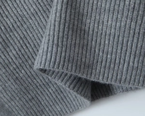 Macro shot of dark grey ribbed knit fabric texture showing high-density woven wool details