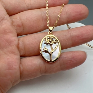 Macro shot of gold oval sunflower pendant necklace with white mother-of-pearl inlay