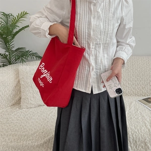 Red canvas tote bag with Bonjour magic print worn with casual outfit on white shirt