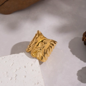 Artistic gold textured elephant ring with abstract sculptural relief on a marble stone base