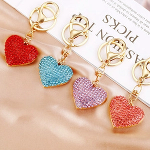 Detail of four crystal heart-shaped keychains in red, blue, purple, and orange pink