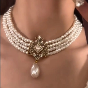 Close-up of four-layer pearl choker with vintage metal filigree and water-drop pendant