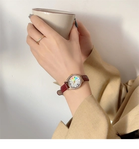 Detail of red leather watch with rainbow dial and rhinestone bezel worn on wrist