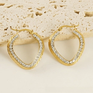 Close-up of gold plated earrings featuring crystal stones and meander pattern