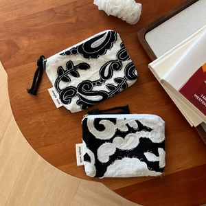 Detailed close-up of embroidered paisley linen wallets with simple wish brand tag