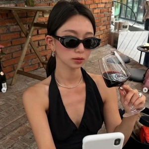 Detail shot of a black oval frame sunglasses paired with a sleek black halter top