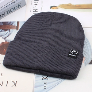 Close-up of dark grey ribbed knit beanie with TF CLASSIC label on magazine background