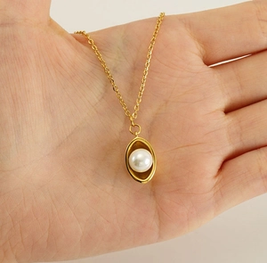 Gros plan détaillé d'un collier de perles plaqué or 18 carats tenu en main