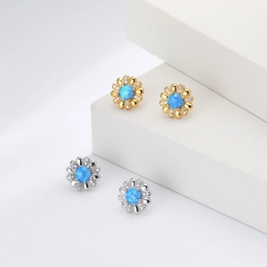 Makroaufnahme von Blumen-Ohrsteckern in Silber und Gold mit blauem Opal und Zirkonia