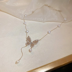 Detail of gold butterfly necklace featuring freshwater pearls and zircon tassel drop
