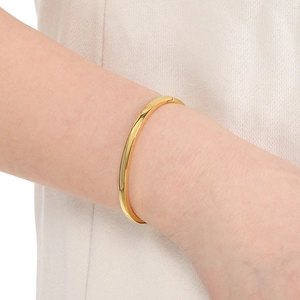 Close-up of minimalist 18k gold plated stainless steel curved bangle on a wrist