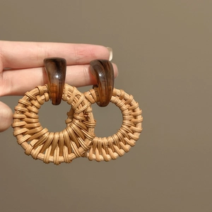 Detail of round rattan earrings with dark brown resin stud and woven texture