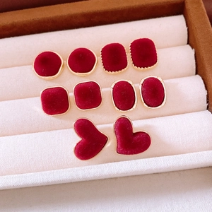 Close-up of vintage deep red flocked earrings in various geometric shapes with gold edges