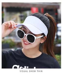 Detailed view of white sun visor hat and round sunglasses with V logo on model