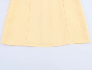 Dettaglio ravvicinato del tessuto tweed giallo con trama intrecciata e cuciture pregiate