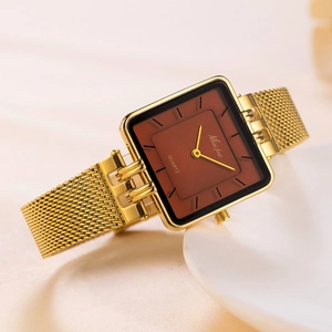 Detail of square gold watch with brown dial and mesh strap on a white stand