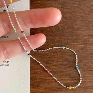 Macro shot of 925 sterling silver chain featuring colorful beads held by fingers