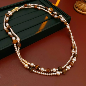 Détail montrant les couches de perles blanches et de perles d'œil de tigre sur le collier