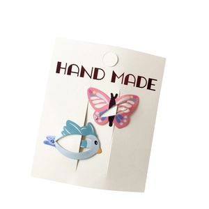 Cute pink butterfly and blue bird enamel metal hair clips on a white card