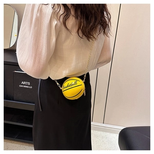Detailed view of yellow basketball shape crossbody bag with gold chain strap worn by a model