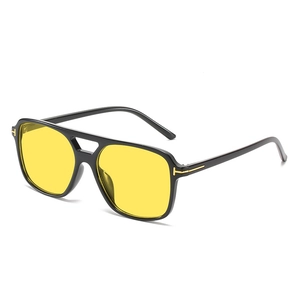 Black pilot sunglasses with yellow lenses and golden T-shaped metal hinges on white background