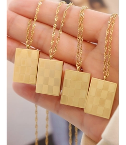 Macro view of gold plated rectangular pendants featuring checkerboard texture and twist chains