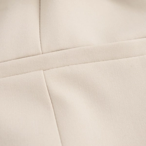 Detailed macro view of beige woven fabric texture and stitching on sleeveless dress