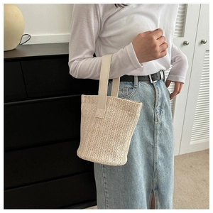 Detail of hand-woven straw bucket bag with reinforced faux leather handles for summer