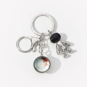 Detailed view of silver astronaut charm and planet pendant on a metal keychain