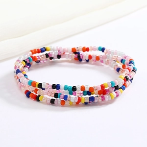 Macro shot of three colorful beaded elastic waist chains on a clean white fabric background