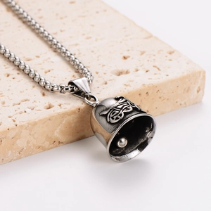 Vintage stainless steel motorcycle bell pendant on box chain over a beige stone